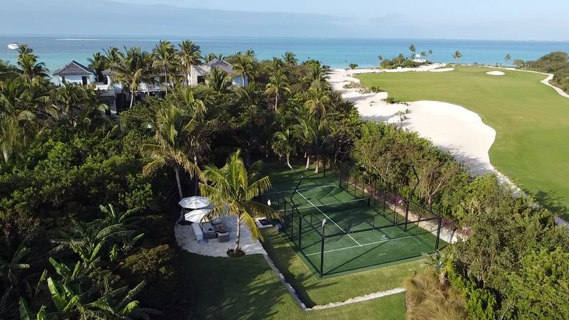 A padel court among palm trees by the ocean, seen from above
